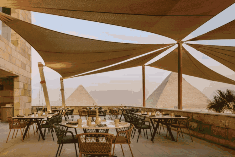 Outdoor terrace dining at Khufu’s Restaurant overlooking the Pyramids of Giza at sunset in Cairo.