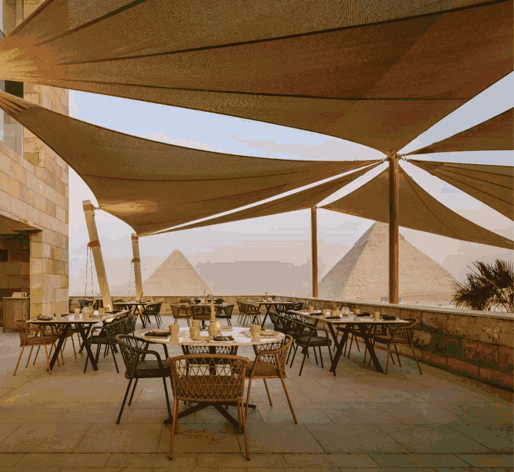 Outdoor terrace dining at Khufu’s Restaurant overlooking the Pyramids of Giza at sunset in Cairo.