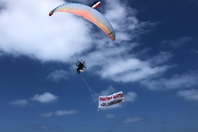 Paragliding advertising campaign over the Red Sea in Egypt with a branded promotional flag flying above the beach